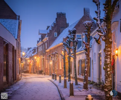 Snowy Morning in Amersfoort | A thin layer of snow turns the canals and cobbled streets into a quiet winter postcard, with warm lantern light glowing against the blue dawn